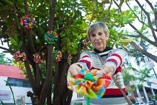A aposentada Juza Pádua espalha flores de chita em uma arvore no bairro Anchieta