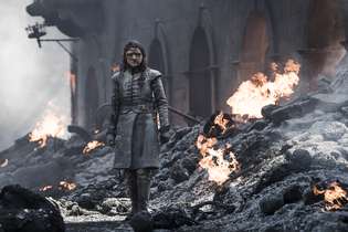 Arya, personagem de  Maisie Williams, caminha sobre as ruínas de Porto Real
