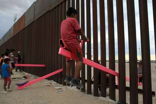 Crianças do México e dos EUA brincam com gangorra instalada no muro da fronteira