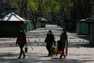 Mulheres de máscaras caminham pelo bulevar Las Rambas, em Barcelona, durante o lockdown na Espanha