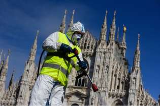 Com o objetivo de conter a propagação do Covid-19, funcionário da AMSA pulveriza desinfetante na Piazza Duomo, em Milão