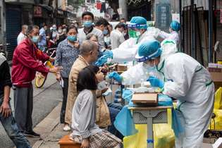 Profissionais de saúde coletam material para exames numa rua de Wuhan, na China, primeiro epicentro da epidemia no mundo