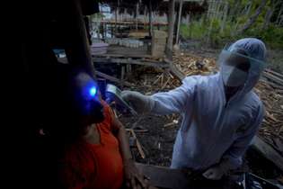 Profissionais de saúde examinam uma mulher com sintomas de Covid-19 na Ilha Marajó, Pará