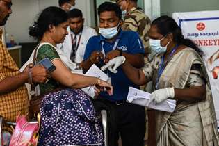 Funcionários da área de saúde em aeroporto na Índia examinam passageiros que chegam, em busca de sinais e sintomas da varíola dos macacos
