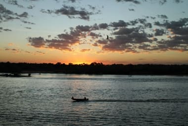 Bote a motor desce o rio ao pôr do sol: uma imagem típica